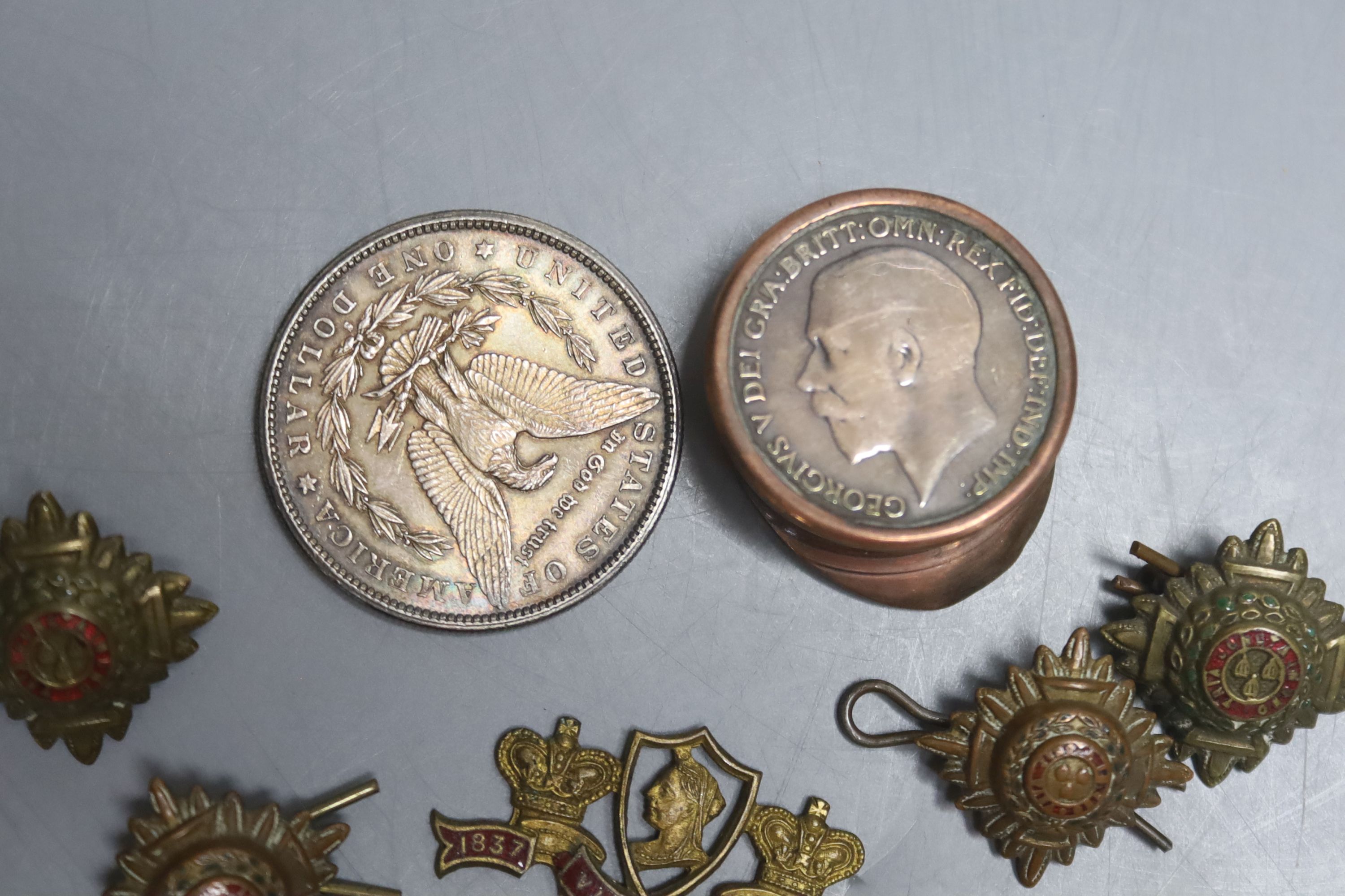 A US silver dollar 1881, five regimental buttons and a badge, copper penny cap